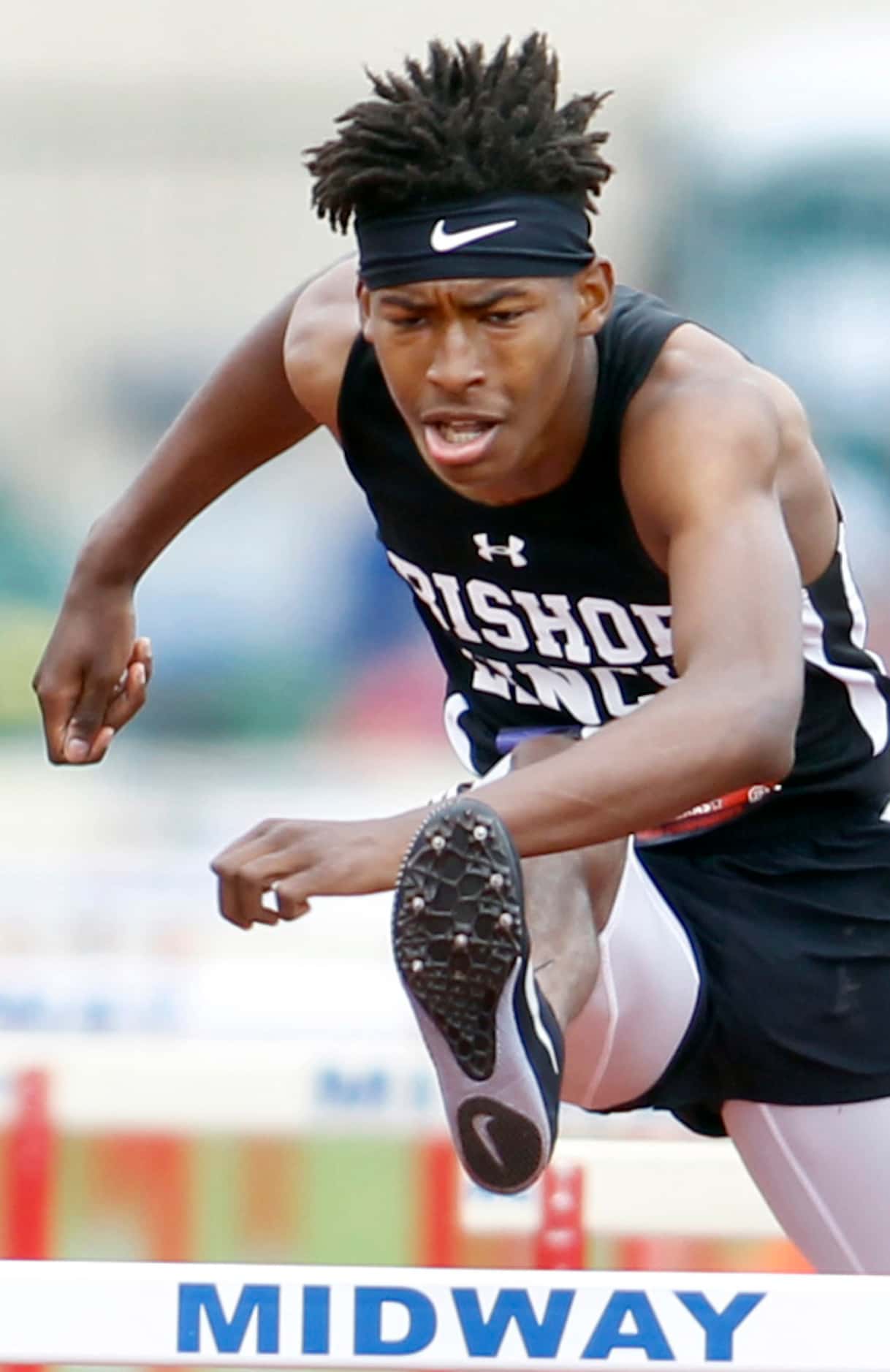 Bishop Lynch hurdler Jeremiah Williams clears a hurdle enroute to his first place finish in...