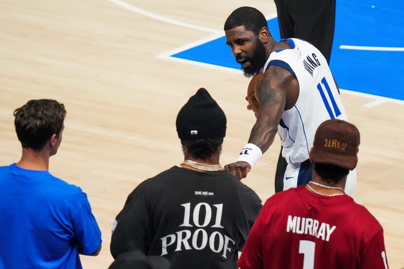 Dallas Mavericks guard Kyrie Irving (11) fits bumps Arizona Cardinals quarterback Kyler...