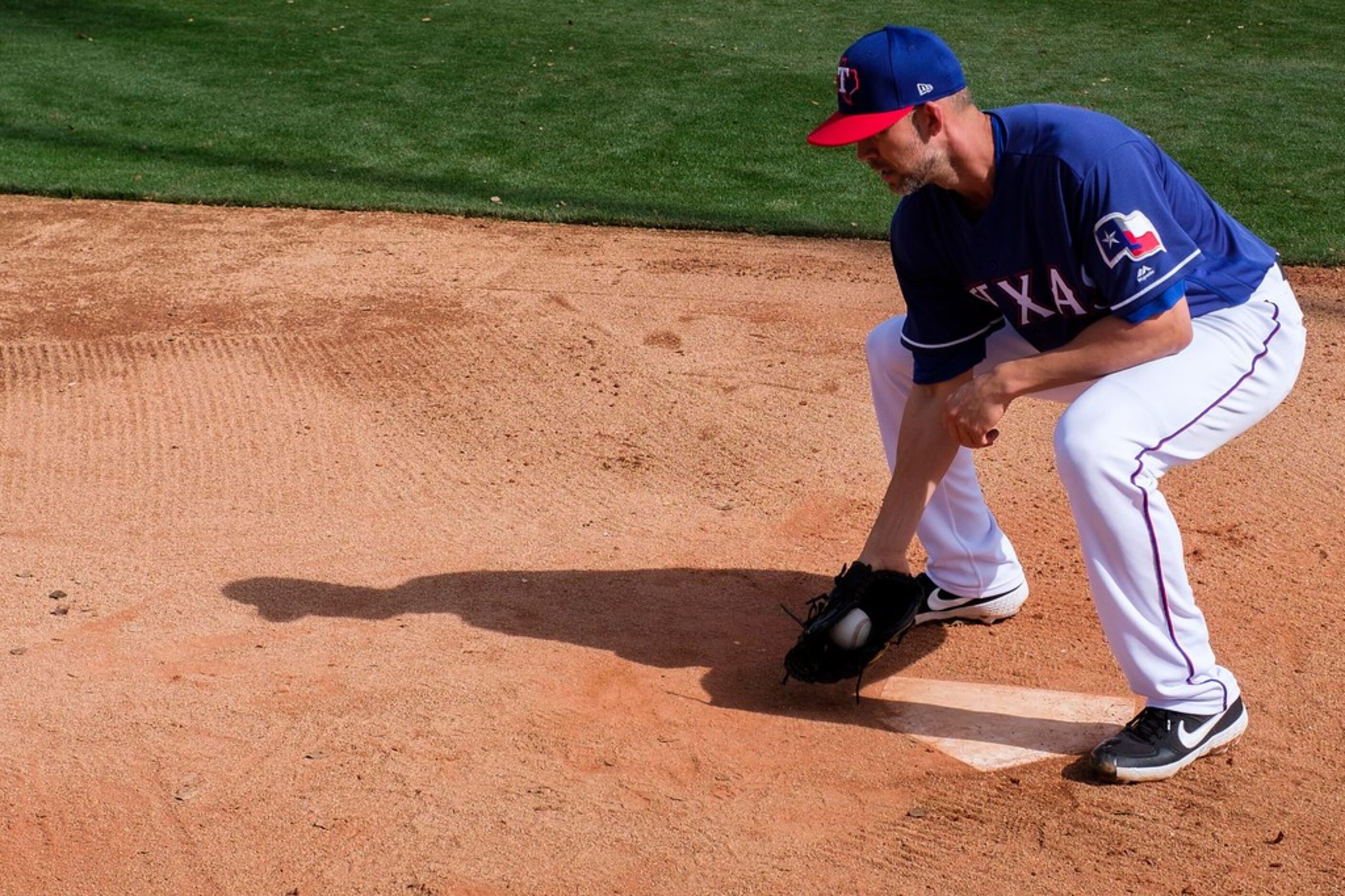 Texas Rangers pitcher Mike Minor participates in a fielding drill during a spring training...