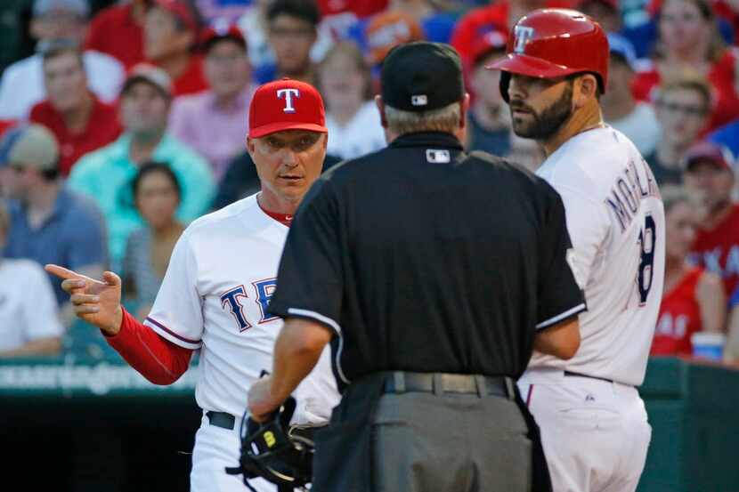 Texas manager Jeff Banister, left, questions home plate umpire Jim Joyce, as does batter...