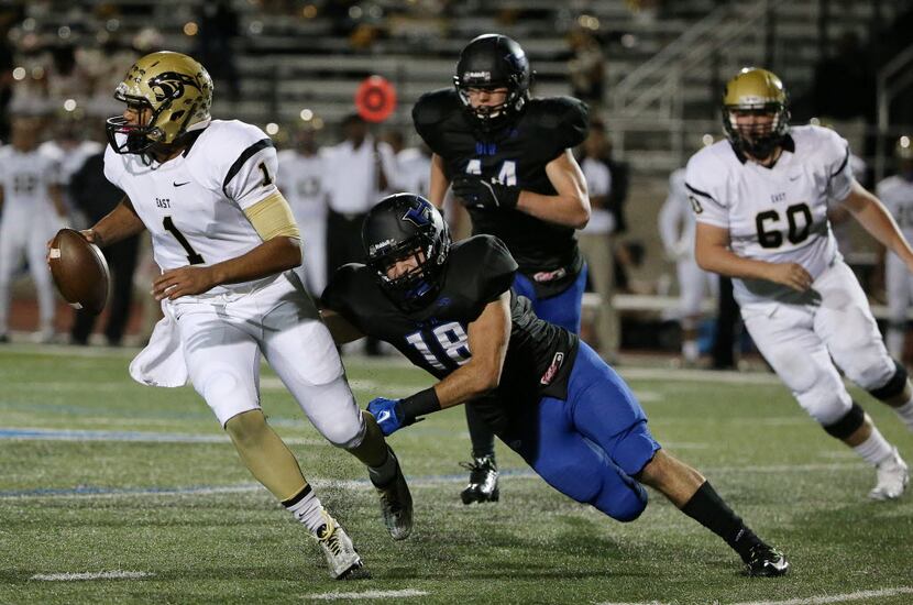 Plano East quarterback Miklo Smalls (1) maneuvers with the ball while being covered by...