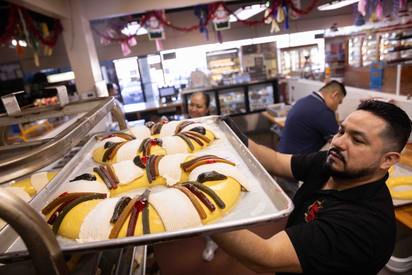 Co-owner Francisco Tapia sets decorated Rosca de Reyes (Three Kings' Cake) onto a pan rack...