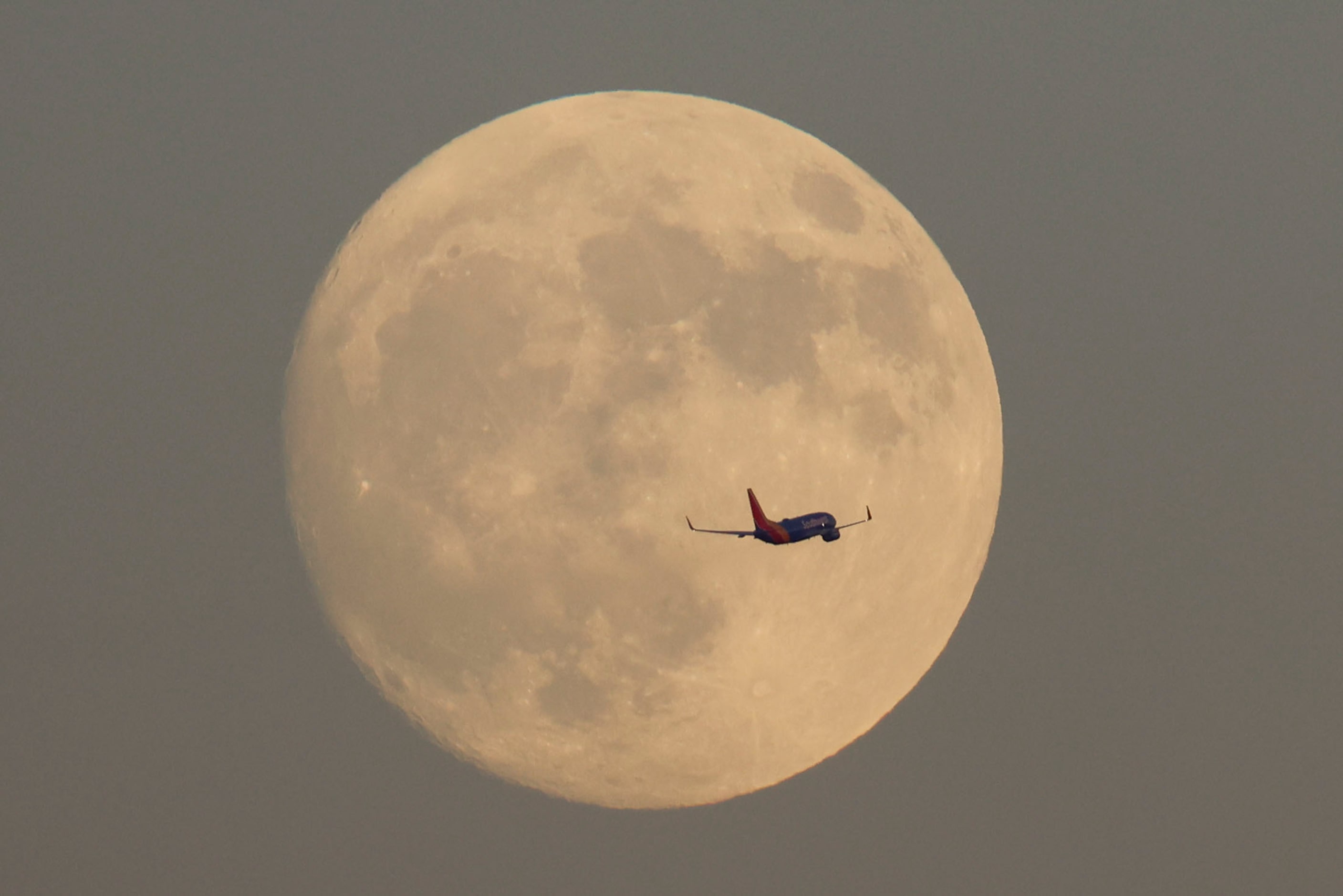 A Southwest Airlines jet passes by a partially full Super harvest moon, on Monday, Sept. 16,...