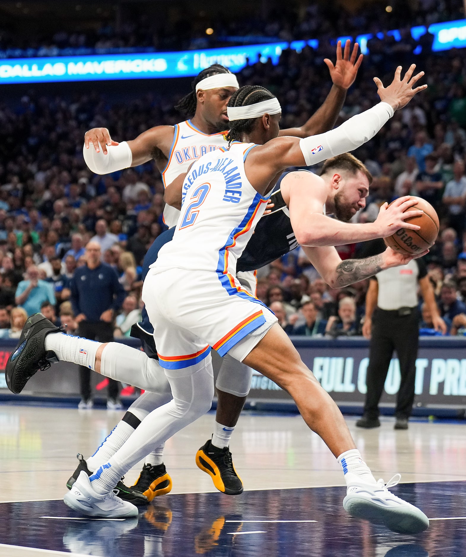 Dallas Mavericks guard Luka Doncic (77) drives to the basket between Oklahoma City Thunder...