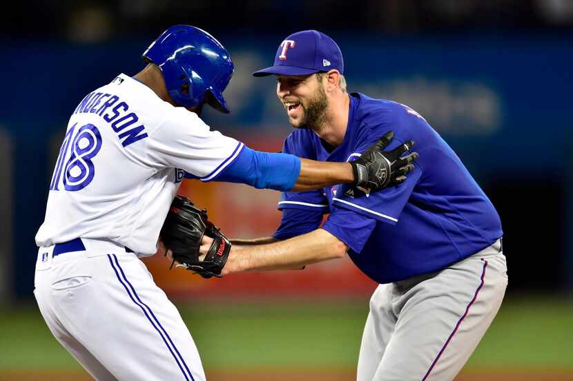 Texas Rangers relief pitcher Chris Martin tags out Toronto Blue Jays' Curtis Granderson (18)...