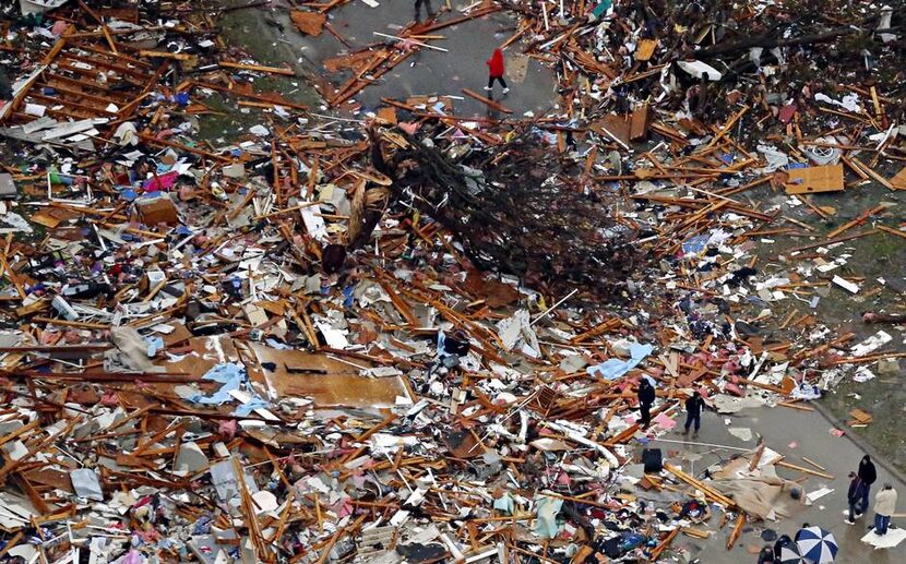  People survey tornado-damaged homes Sunday in Rowlett. Violent storms ripped through North...