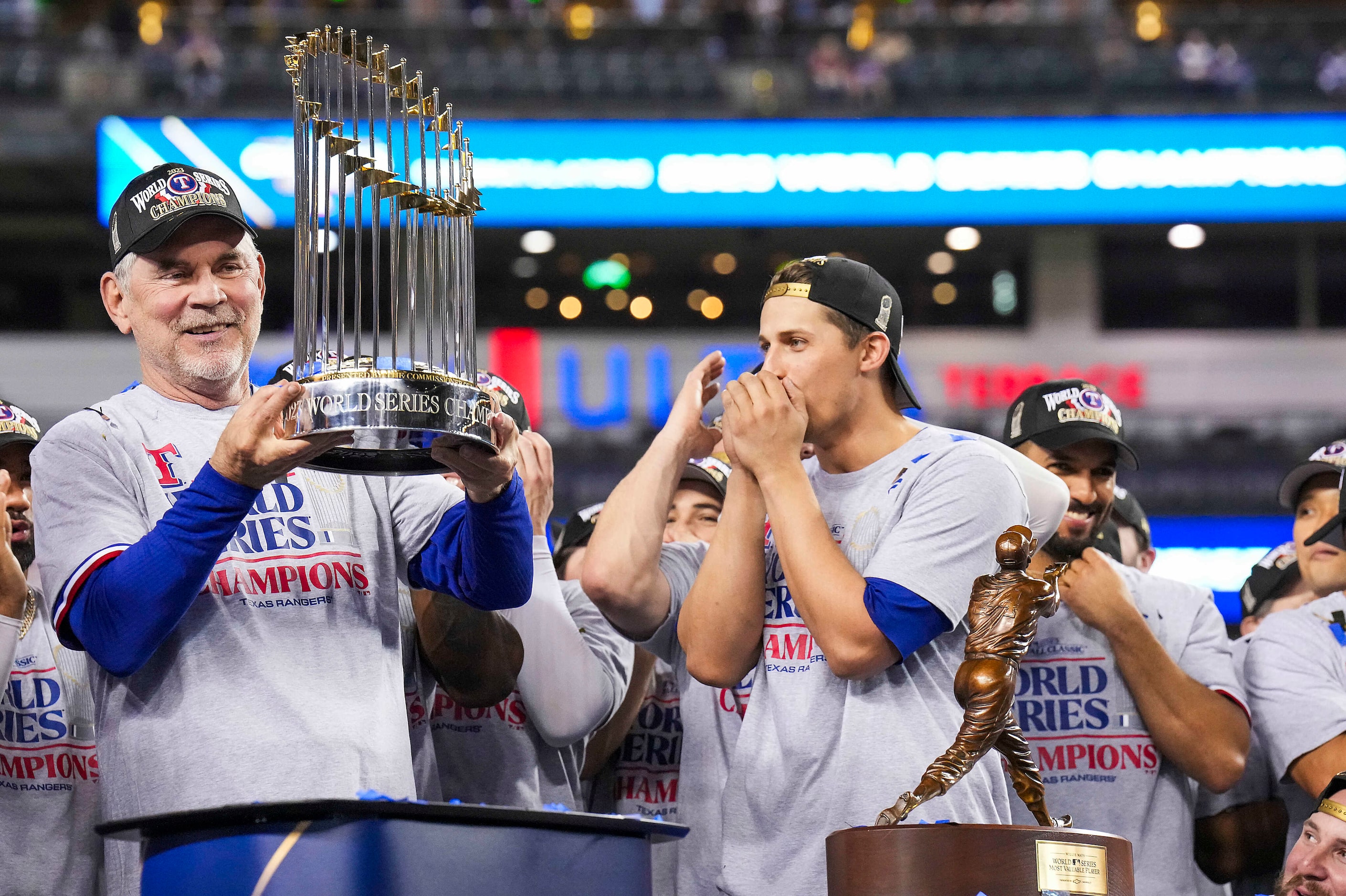 Texas Rangers manager Bruce Bochy holds the Commissioner’s Trophy to the cheers of shortstop...