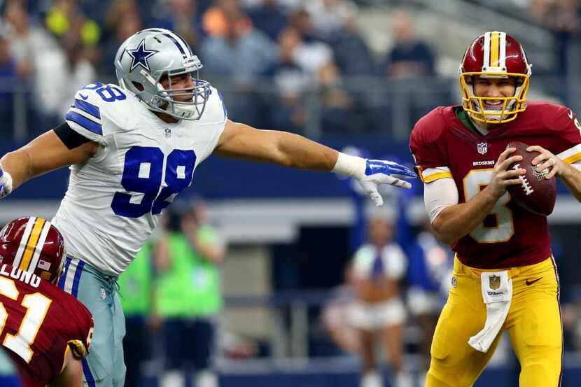 Kirk Cousins #8 of the Washington Redskins escapes from Tyrone Crawford #98 of the Dallas...