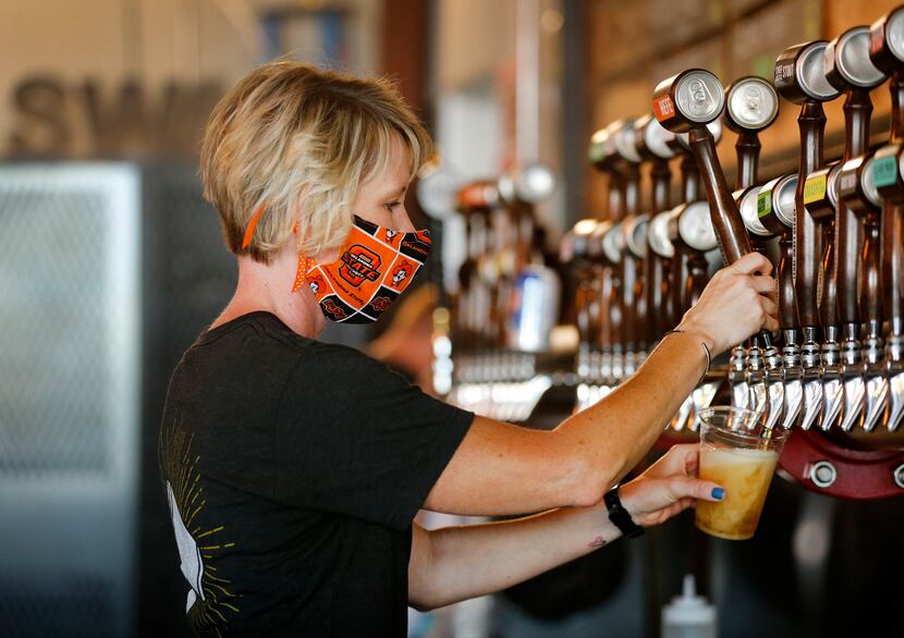 Bartender Rae Huffstetter donned an Oklahoma State University-themed mask while drawing taps...
