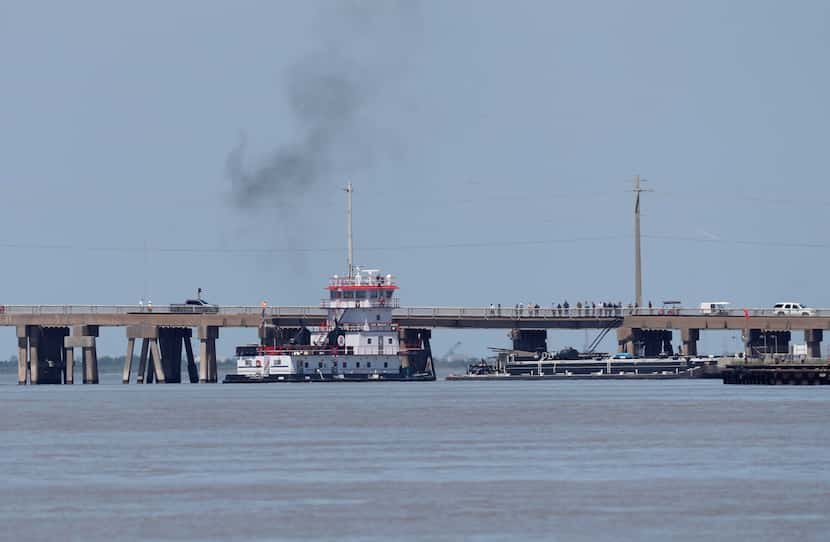 A tugboat works to maneuver a barge away from the Pelican Island Bridge in Galveston, Texas,...