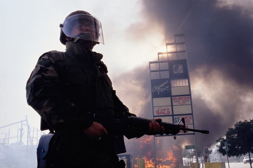 A member of the National Guard stands near burning building during the Los Angeles riots. In...