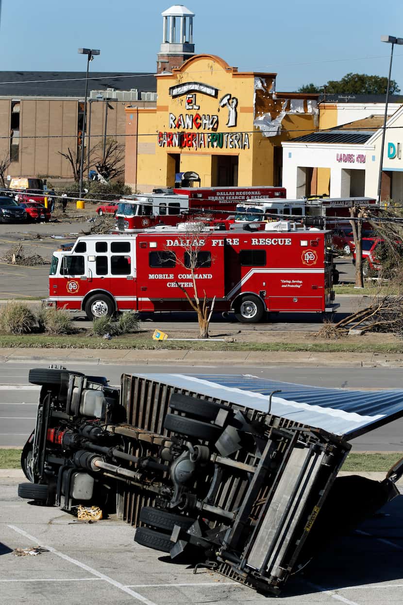 A box truck lays on its side in the shopping center parking lot near the intersection of...