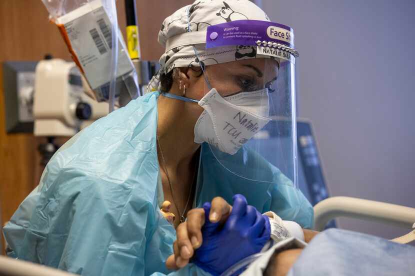 La enfermera Natalie Salazar toma la mano de un paciente en la unidad táctica de covid-19 en...