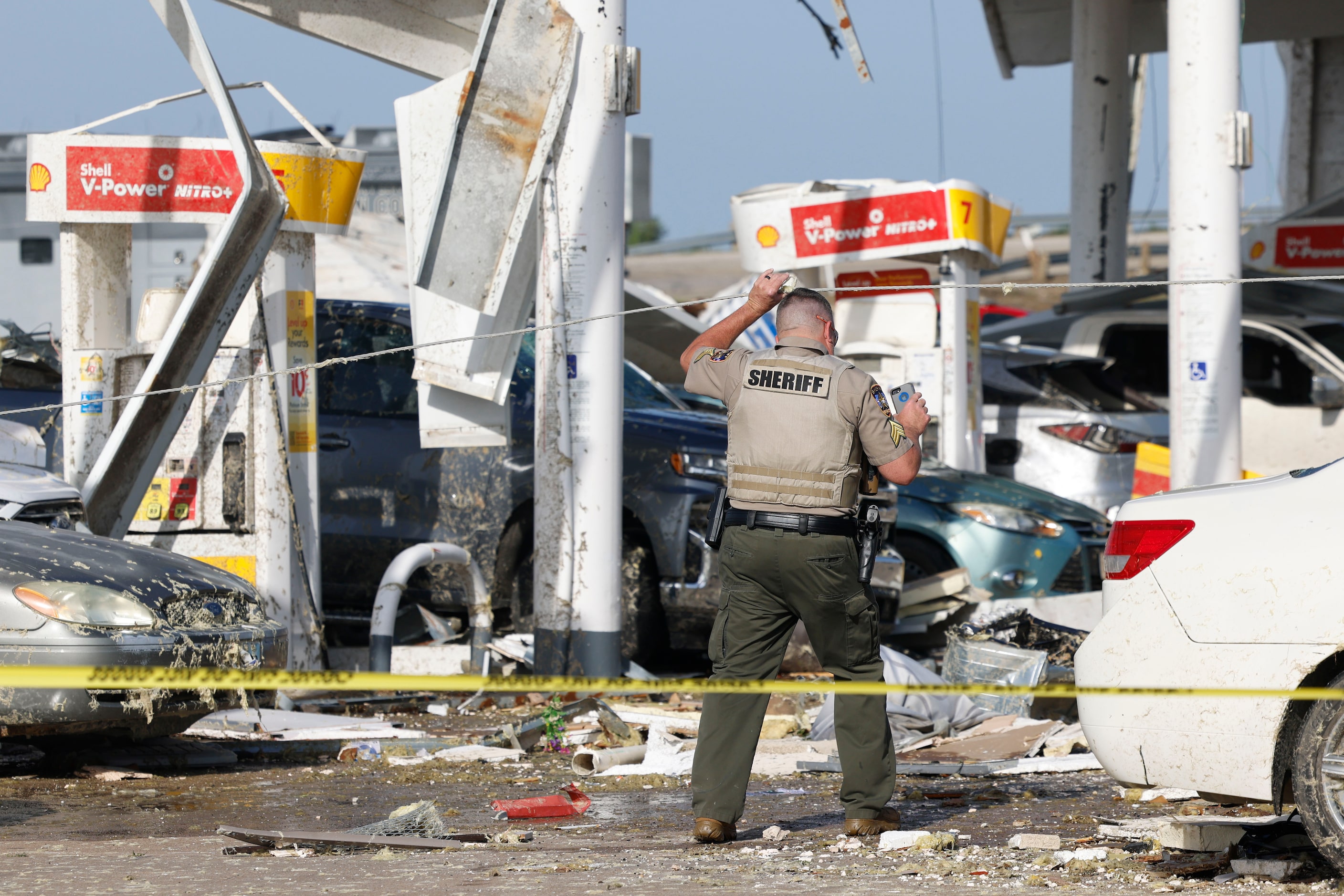 Law enforcement authority members scout a heavily damaged Shell gas station, on Sunday, May...