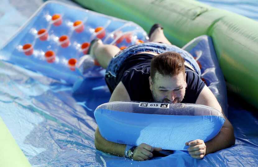 Andy Anders slides down a 1,000 foot water slide during the Slide the City event in the 3400...