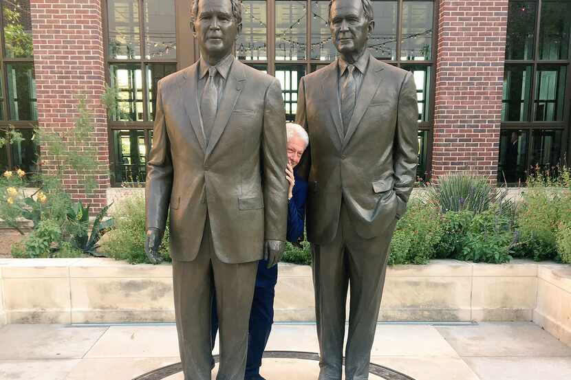 Former President Bill Clinton poses for a funny photo behind statues of former Presidents...