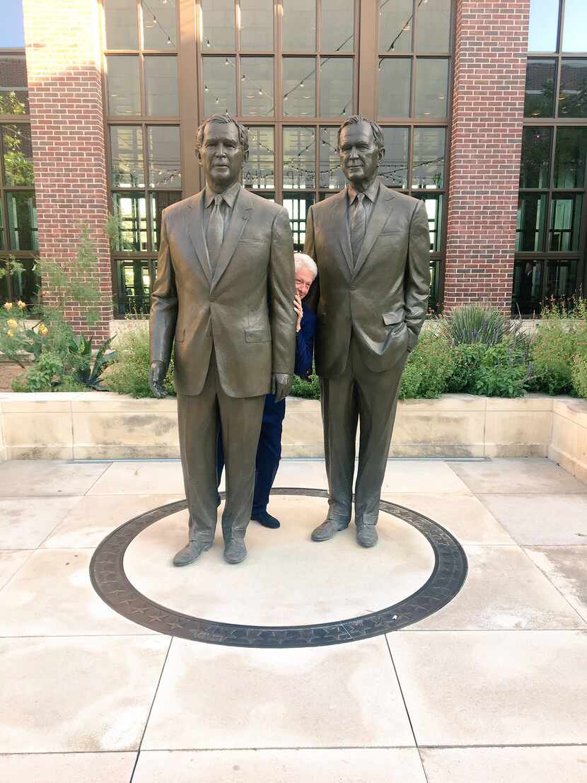 Former President Bill Clinton poses for a funny photo behind statues of former Presidents...