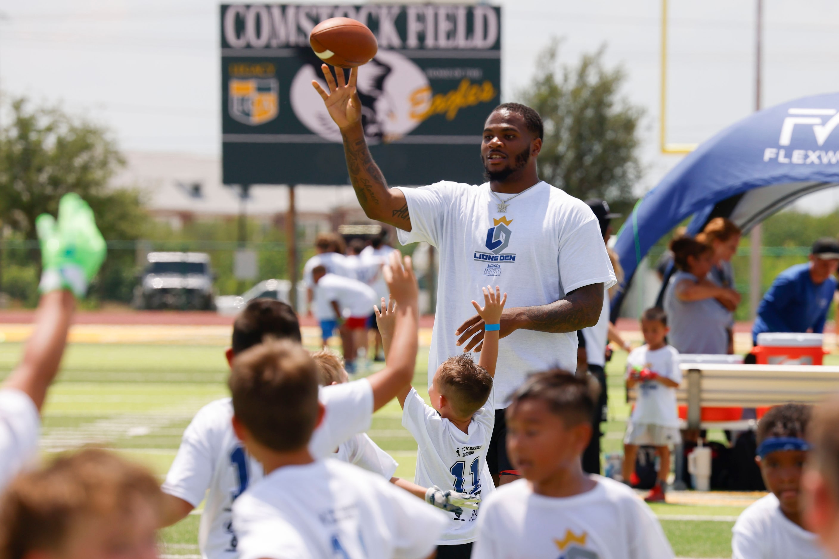 Dallas Cowboys linebacker Micah Parsons throws the ball as he interacts with young football...