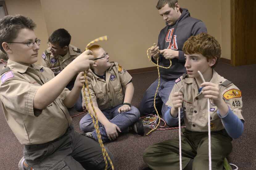 Scouts help one another as they practiced tying knots during a meeting for Boy Scout Troop...