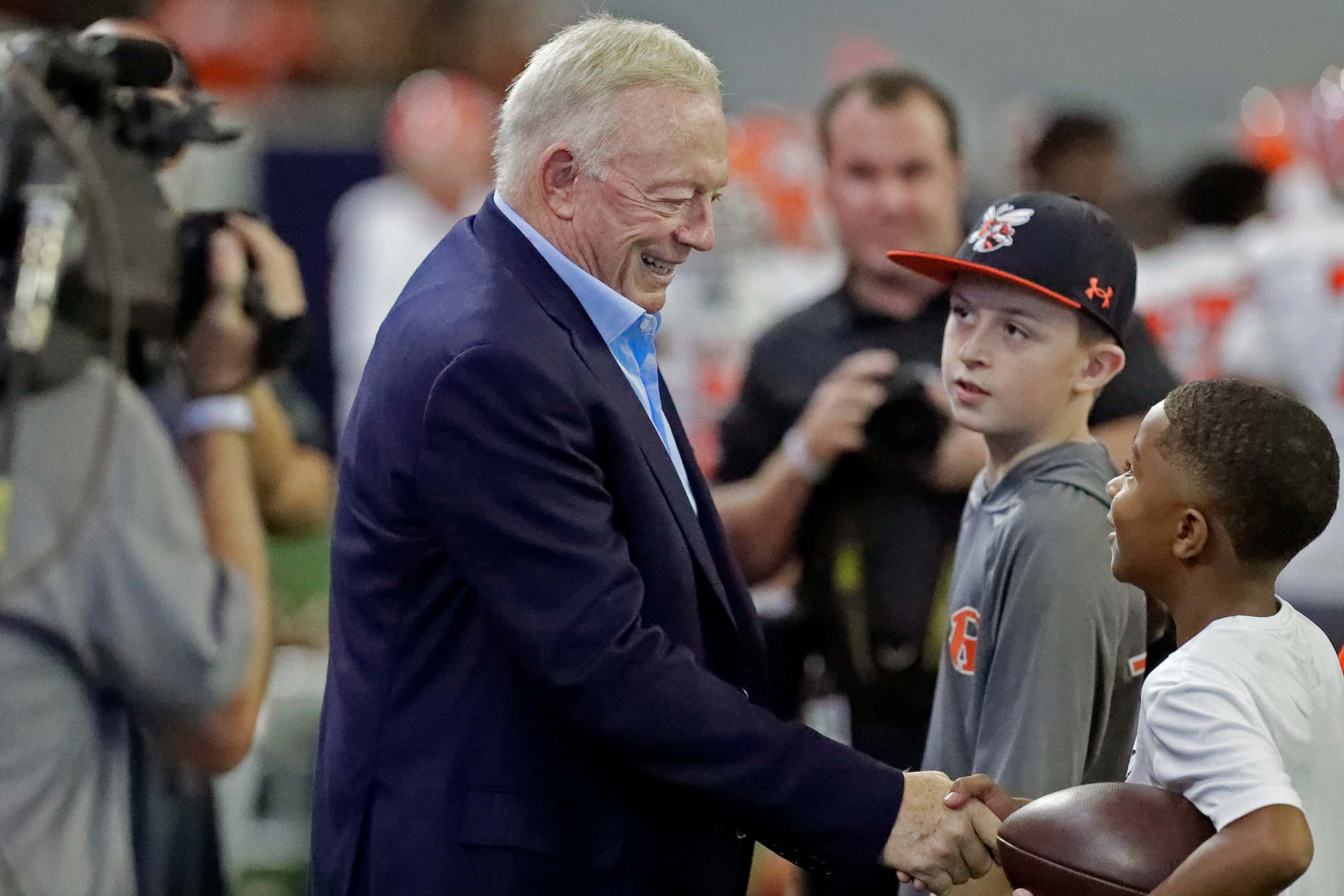 Dallas Cowboys owner Jerry Jones shakes hands with young fans on the sideline before the...