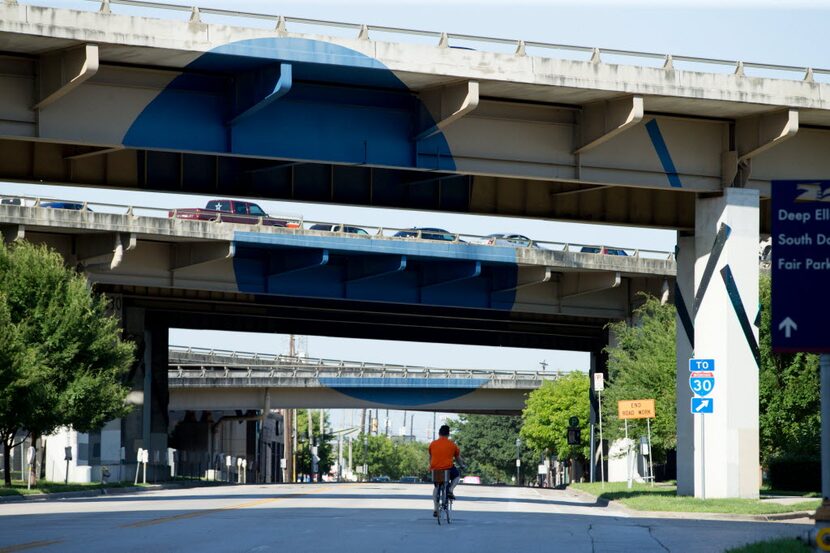 A cyclist rides east bound on Main Street to cross under I-345 and into Deep Ellum on June...