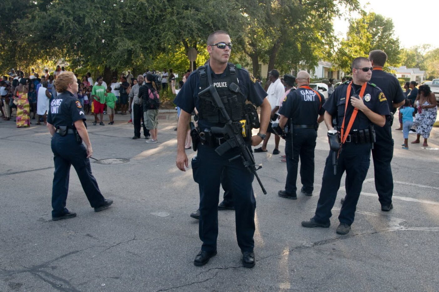 Police carrying assault rifles and pellet guns patrol on Dixon Avenue after an officer...