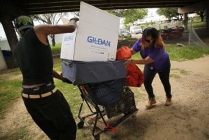  Jasmaine Ingram (right) of the Metro Dallas Homeless Alliance helps a man carry his...