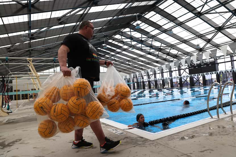Forney High School assistant water polo coach Jason Thompson gathers practice balls to place...