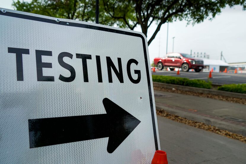 A driver weaves through cones that direct motorists between stations at a Dallas County...