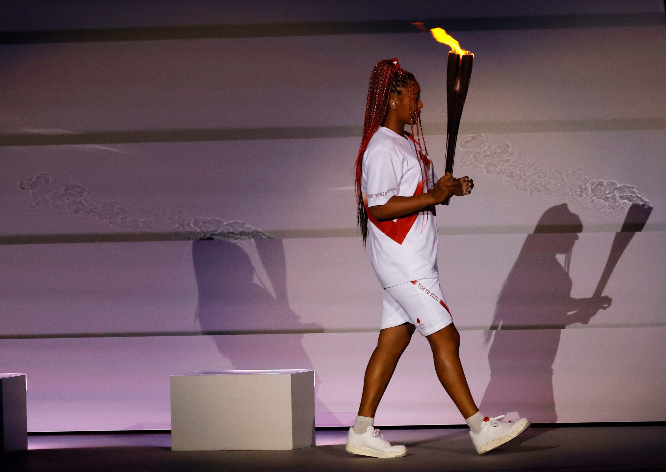 Naomi Osaka carries the Olympic flame during the opening ceremony for the postponed 2020...