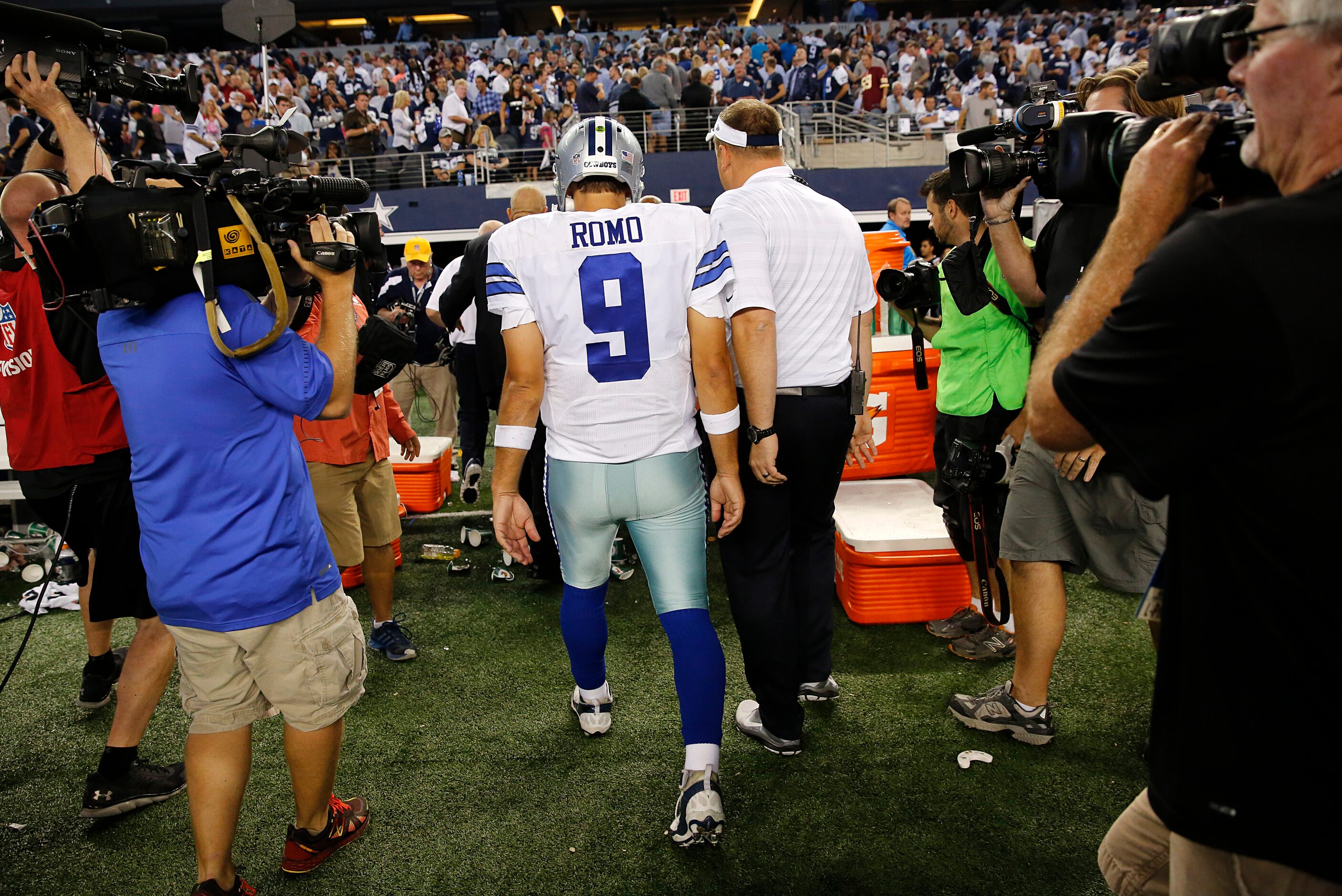 Dallas Cowboys quarterback Tony Romo (9) walks off the field with offensive coordinator...