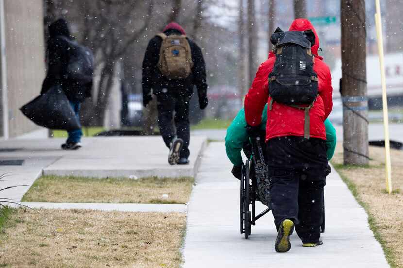 People make their way to Austin Street Center for warmth as snow falls on Thursday, Dec. 22,...