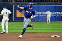 Josh Jung of the Texas Rangers salutes his team's bullpen as he rounds the bases after...