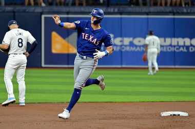 Josh Jung de los Rangers de Texas saluda al bullpen de su equipo al recorrer las bases tras...