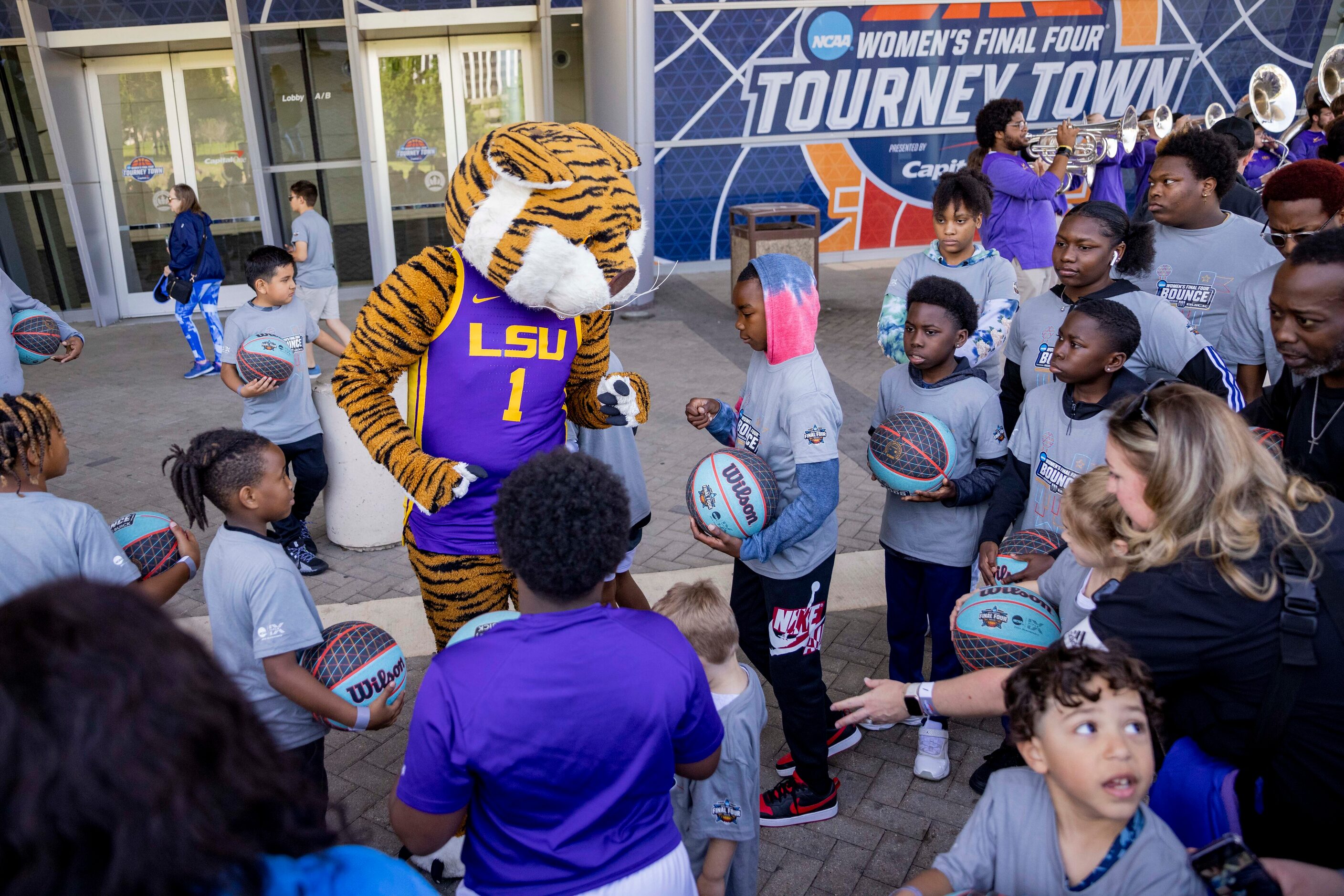 People stop to take photos with LSU’s mascot “Mike the Tiger” after making their way from...