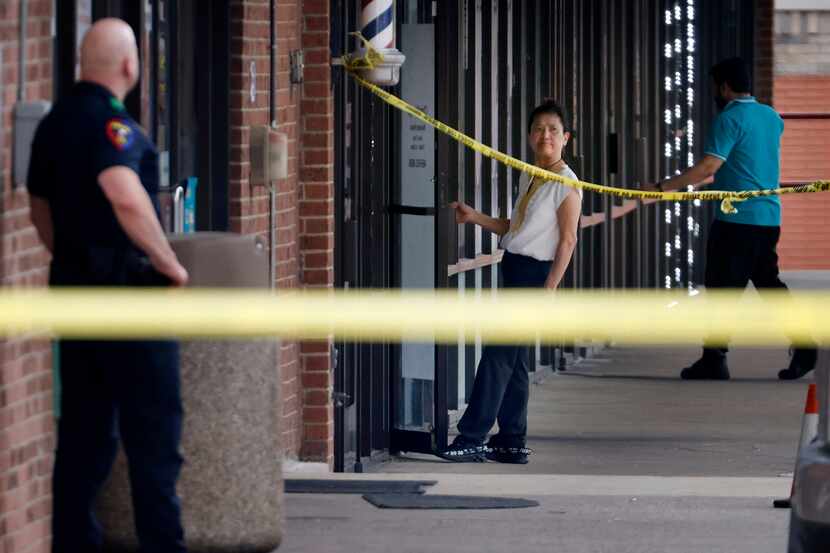 A woman from a nearby business views a Plano police officer standing over a handgun outside...