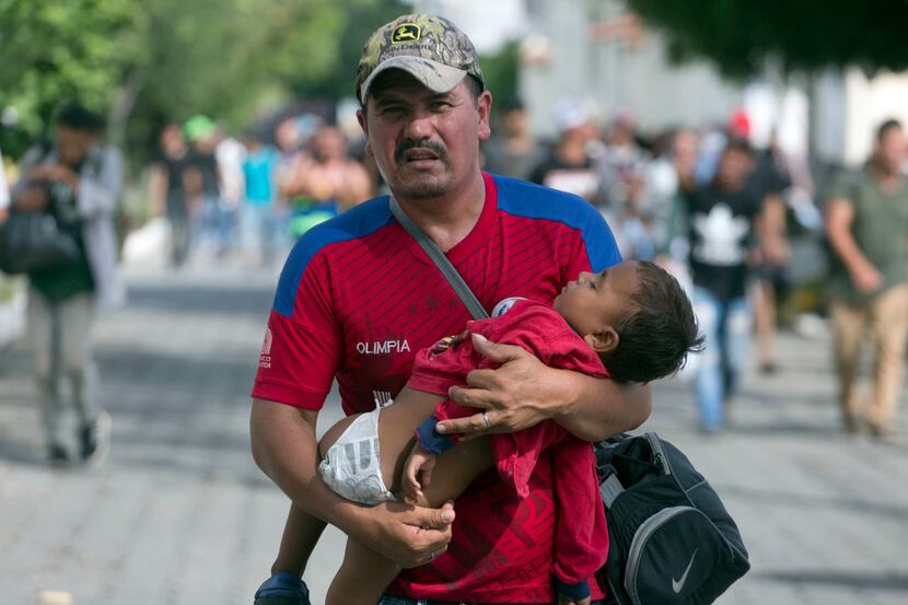 A Honduran migrant carries his son as he walks toward the U.S., in Chiquimula, Guatemala,...