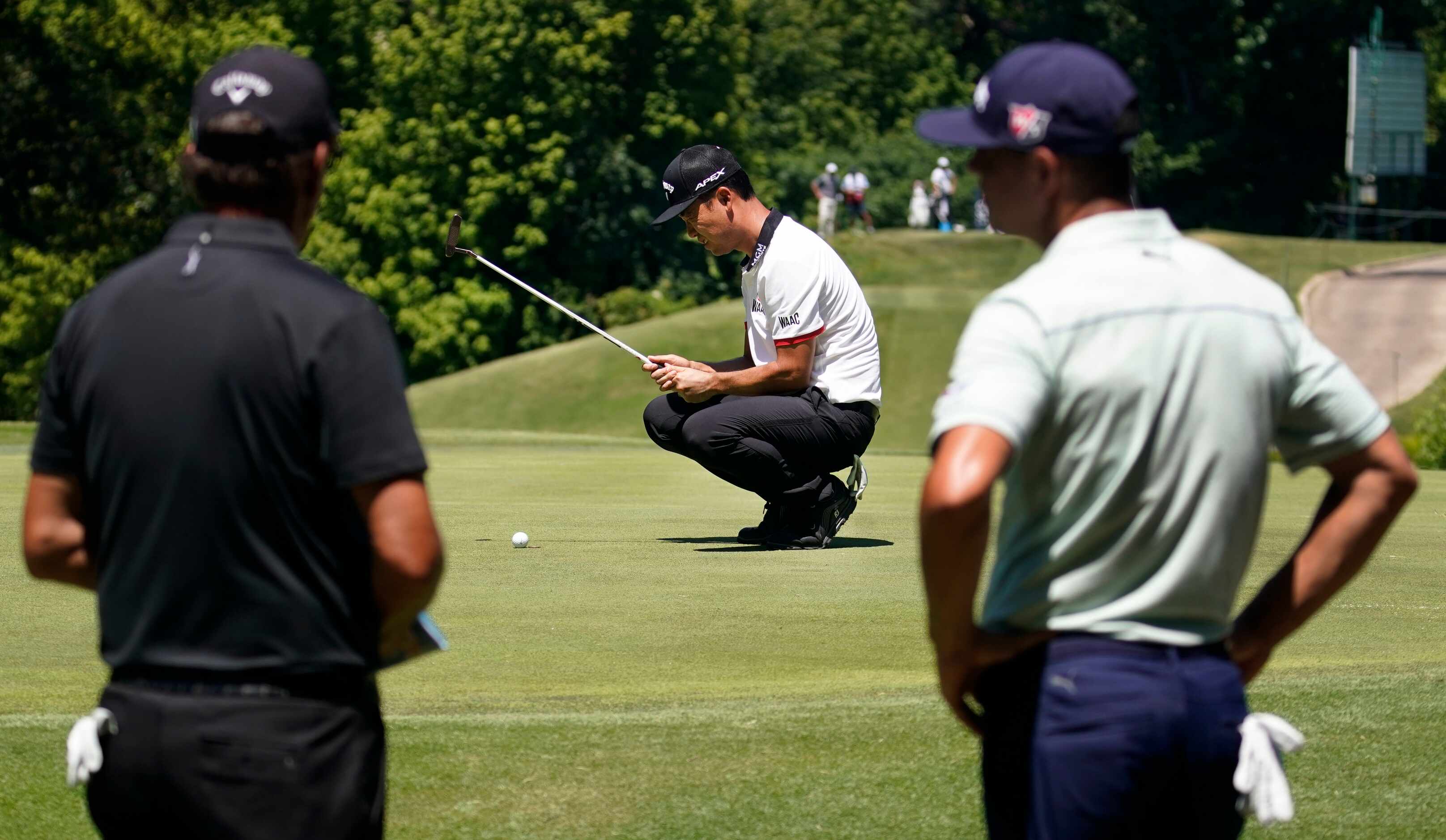 PGA Tour golfer Kevin Na lines up his putt on No. 8 as he plays with Phil Mickelson (left)...