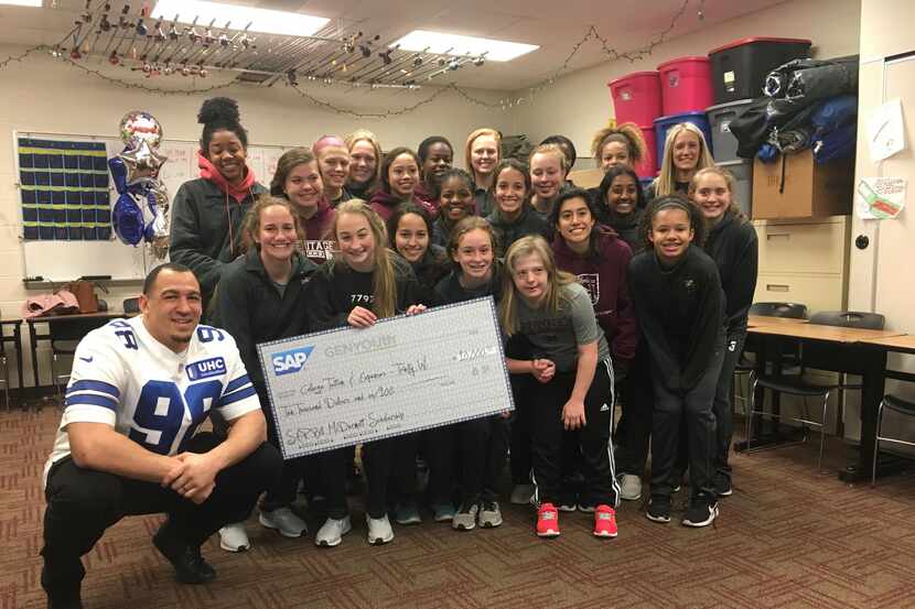Dallas Cowboys defensive lineman Tyrone Crawford poses with the Frisco Heritage girls soccer...