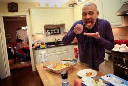 Mike Dimas takes a bite of a homemade tamale at his sister Liz Walker's home. (Rose Baca/The...