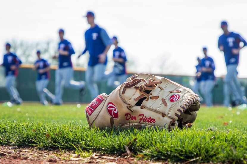 A glove rests near the warning track as Texas Rangers pitchers do conditioning drills during...