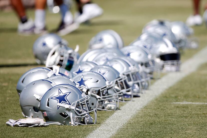 Dallas Cowboys helmets lined up on the field before the start of the afternoon practice at...