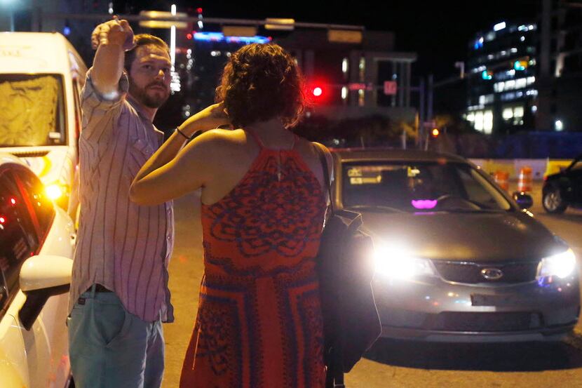  Ryan Murphy and Lindsey Jones looked for the Uber ride they requested on 4th Street in...