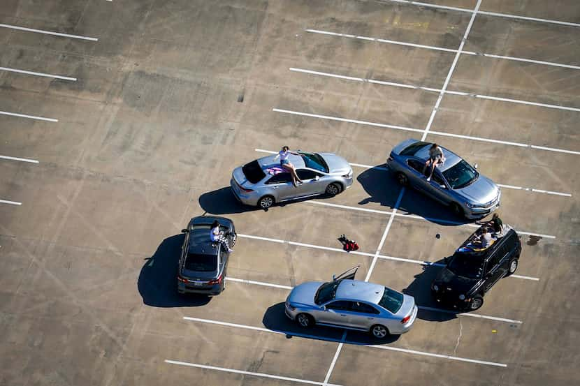 Practicing their own form of social distancing, young people gather in the parking lot of...