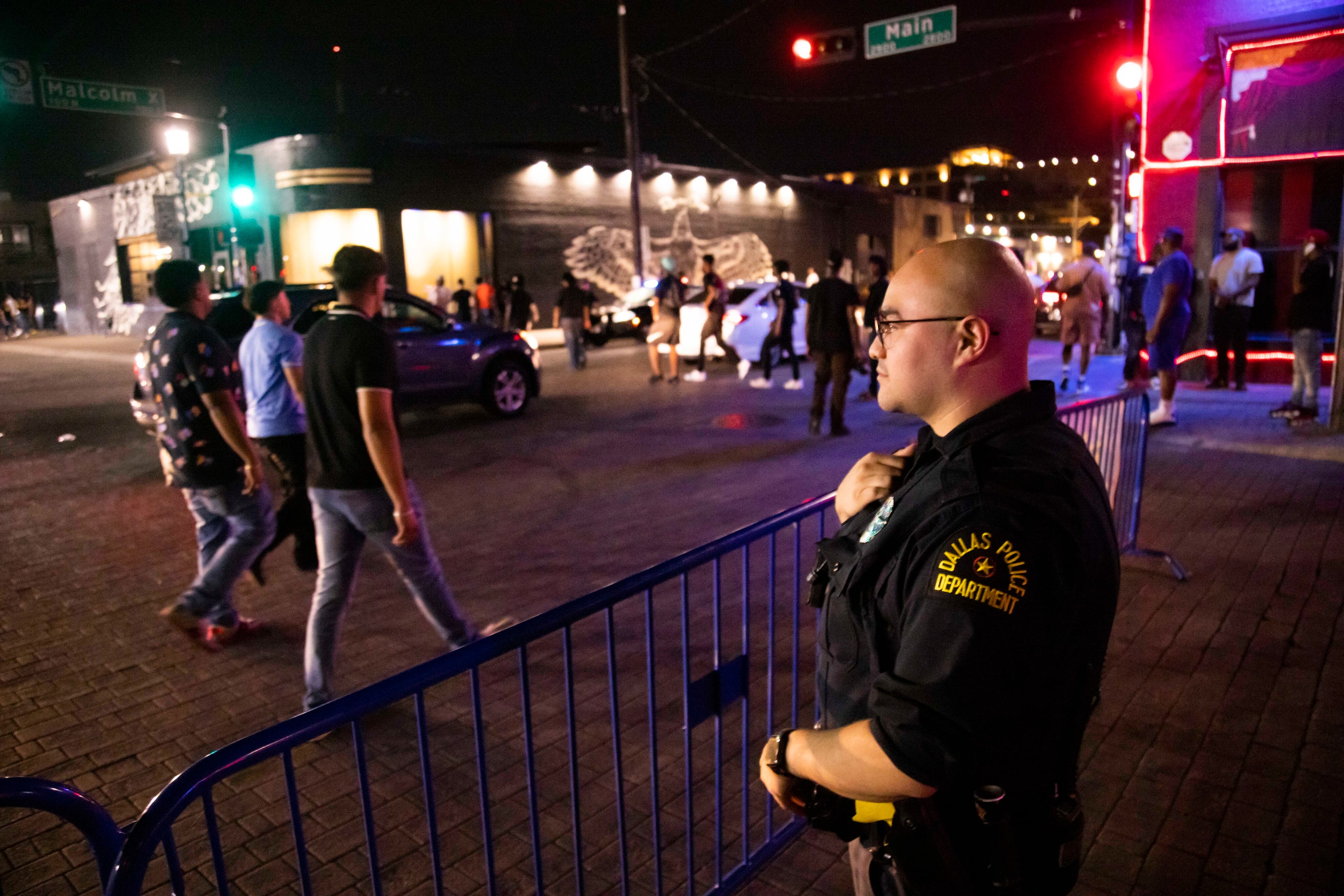 Officer I. Banales watches as people walk in the streets as bars begin to close in the Deep...