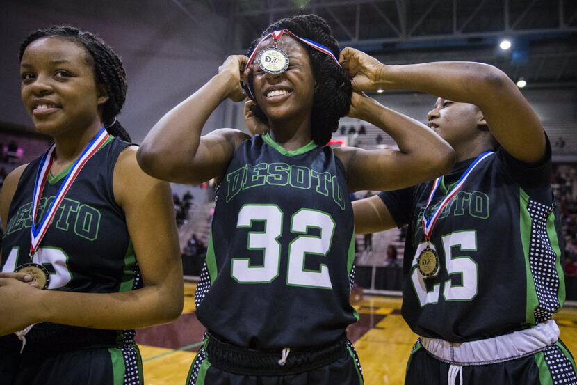 DeSoto's Kiara Collins (25), right, helps Kayla White (32) get a gold medal over her hair...