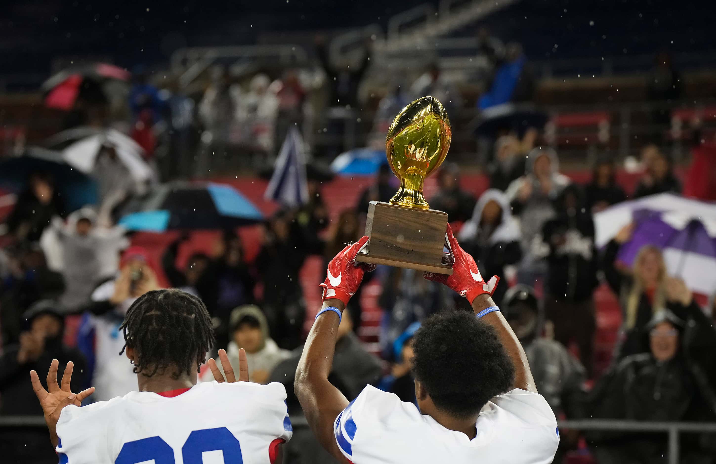 Duncanville defensive back Nick Thompson holds up the game trophy to the crowd after a...