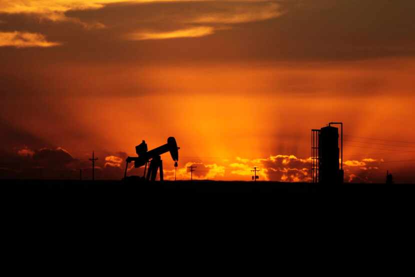Oil well pumpjacks are scattered about the sparse landscape in Loving County, Texas. Shot on...