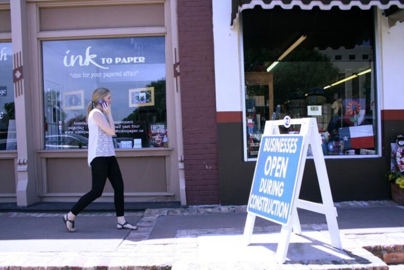 
Signs propped around the square remind shoppers that stores are still open, despite the...