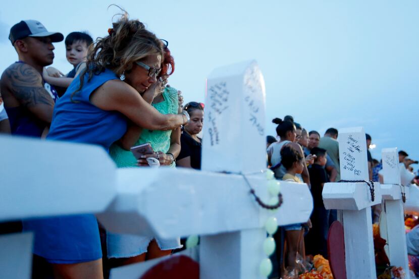 Rebecca Najera hugs Elsa Escobar on Aug. 5 as they joined other mourners gathered beside...